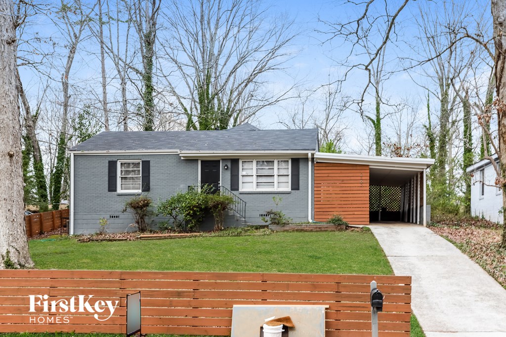 A house with a grey front and a brick wall with a mailbox on it.