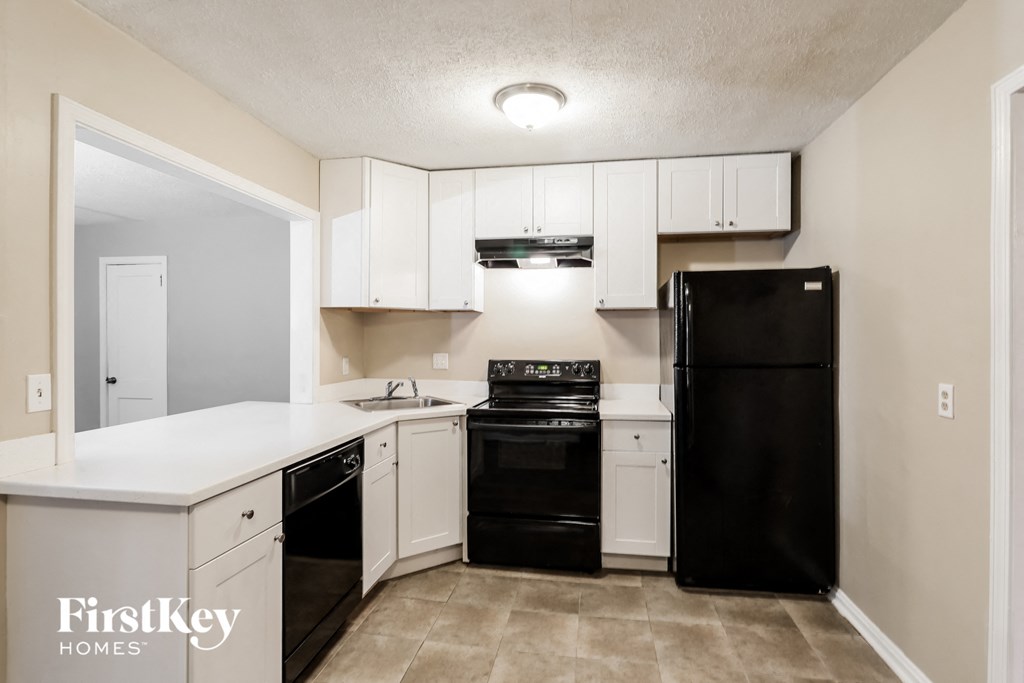 A kitchen with black appliances and white cabinets.