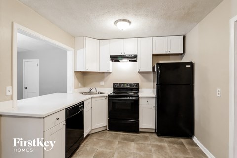 A kitchen with black appliances and white cabinets.