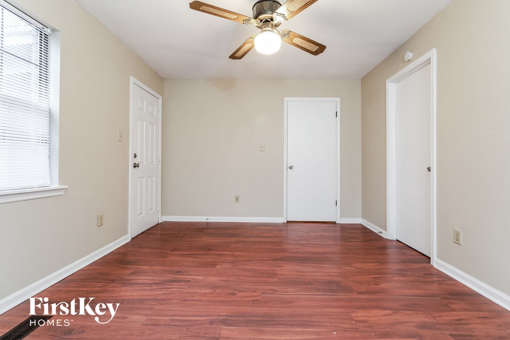 A room with a ceiling fan and wooden floors.