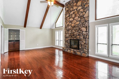 A room with wooden floors and a stone fireplace.