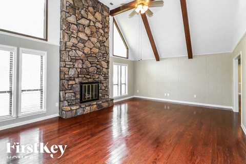 A room with a stone fireplace and wooden floors.