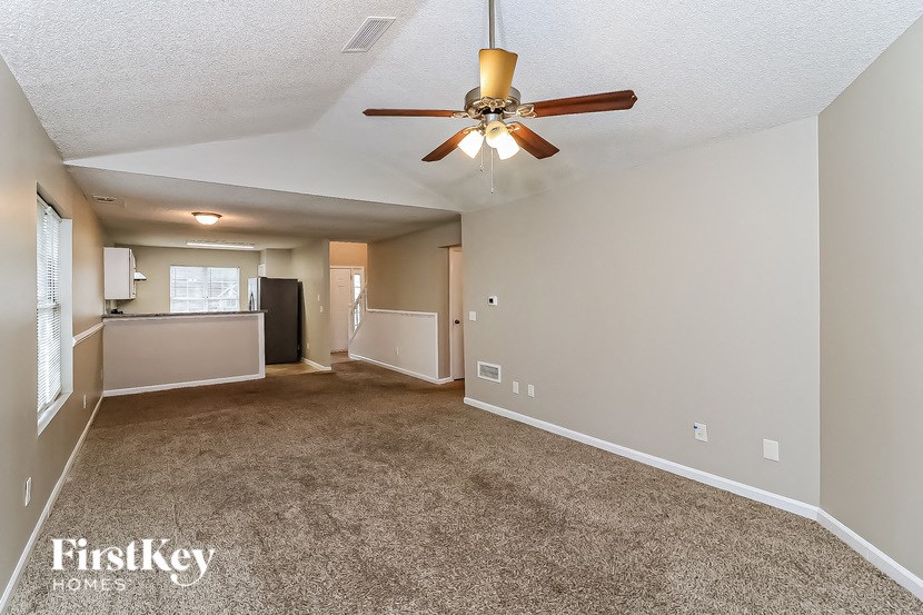 A spacious room with a ceiling fan and carpeted floor.