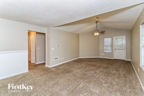 A spacious room with a carpeted floor and a ceiling fan.