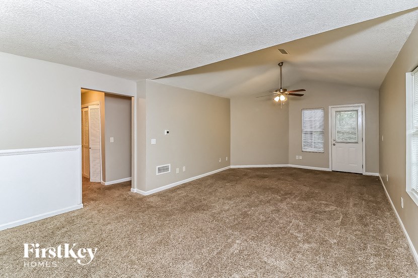 A spacious room with a carpeted floor and a ceiling fan.