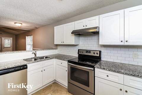 A kitchen with white cabinets and a black stove top oven.