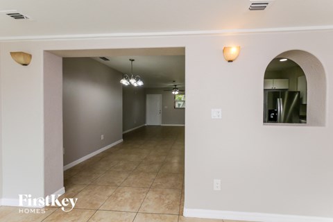 A spacious room with a tiled floor and a large arched doorway leading to another room.