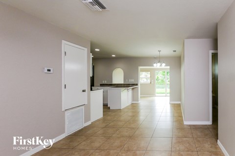 A spacious kitchen and living room with white cabinets and a tiled floor.