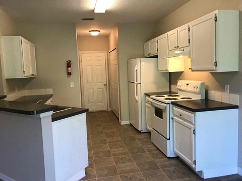 A kitchen with white cabinets and a black counter top.