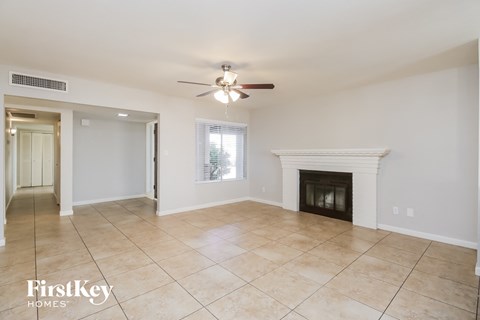A spacious living room with a fireplace and a ceiling fan.