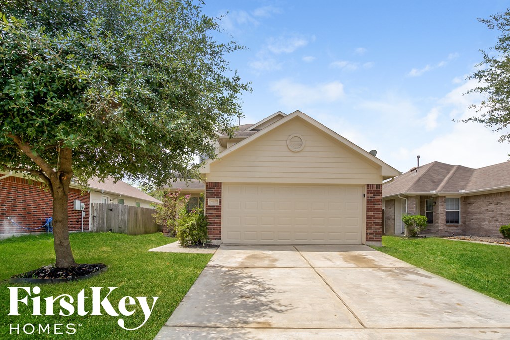 a home with a driveway and a tree in the yard