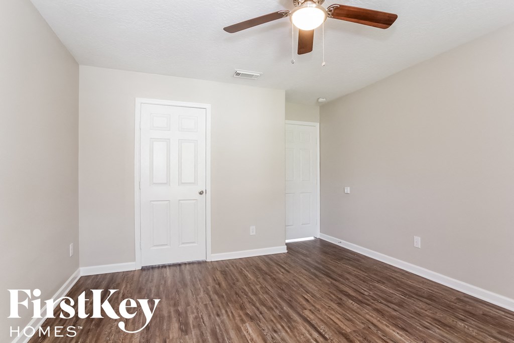 the spacious living room with hardwood flooring and a ceiling fan