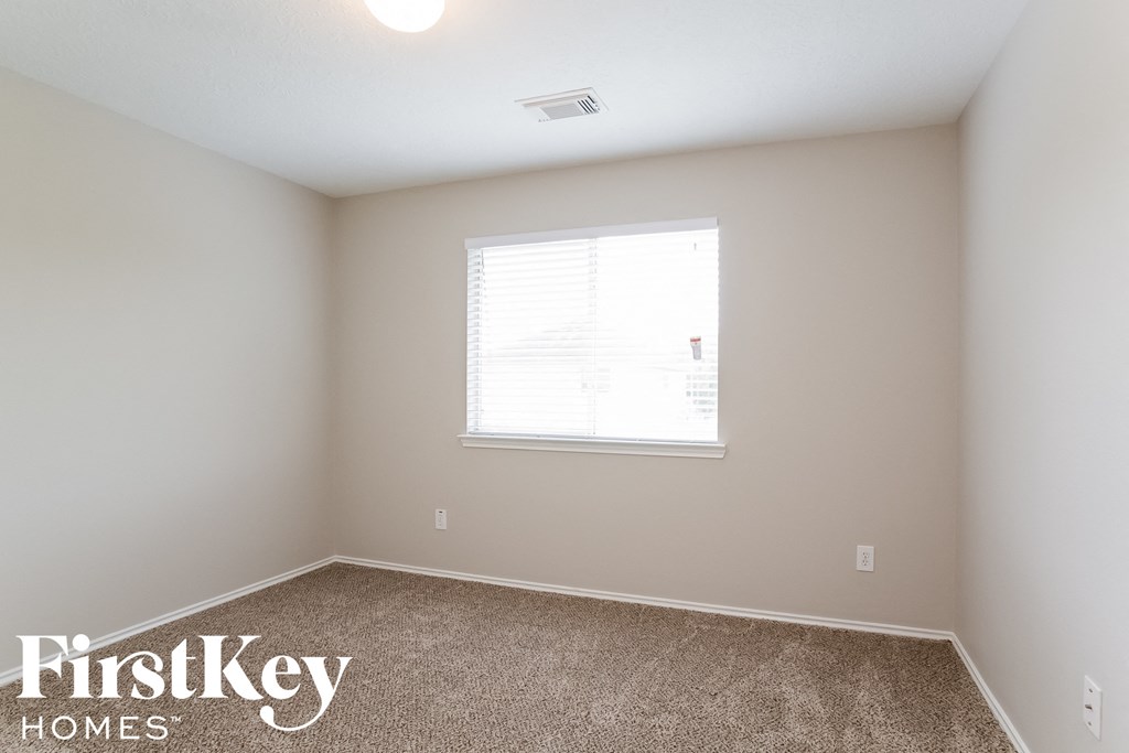 a bedroom with a window and a carpeted floor