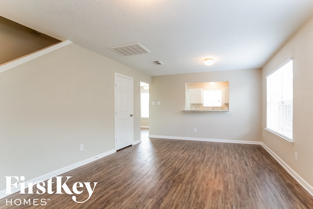 the spacious living room with hardwood flooring and white walls