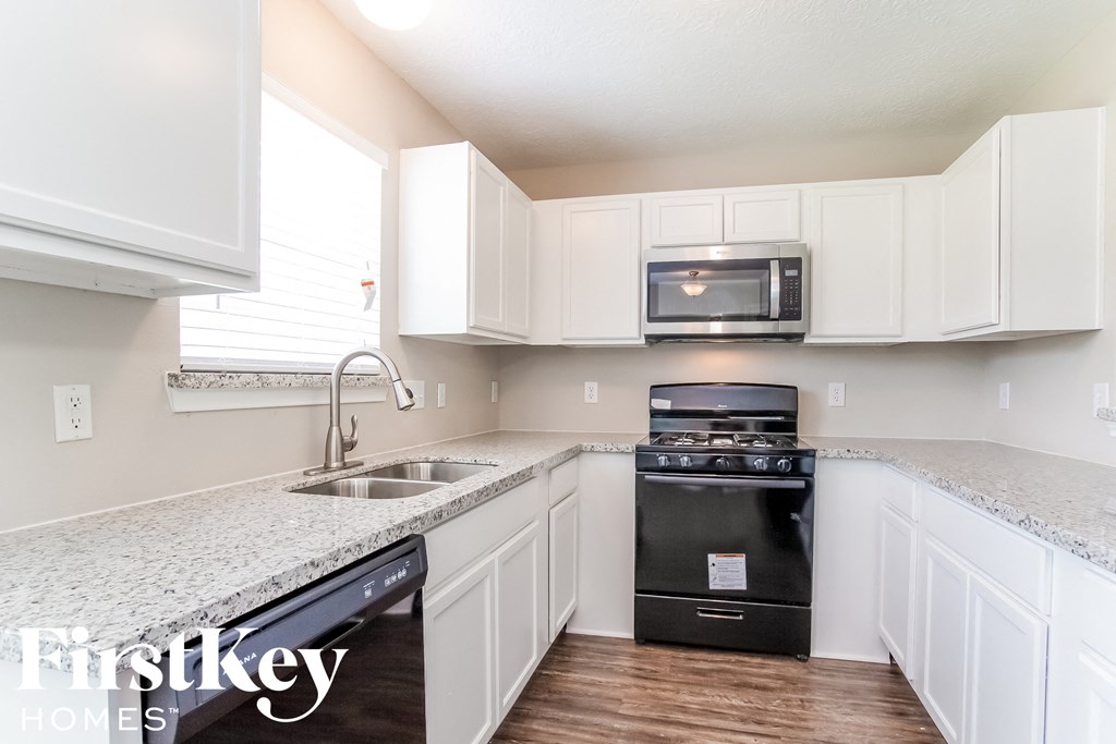 a kitchen with white cabinets and granite counter tops and black appliances