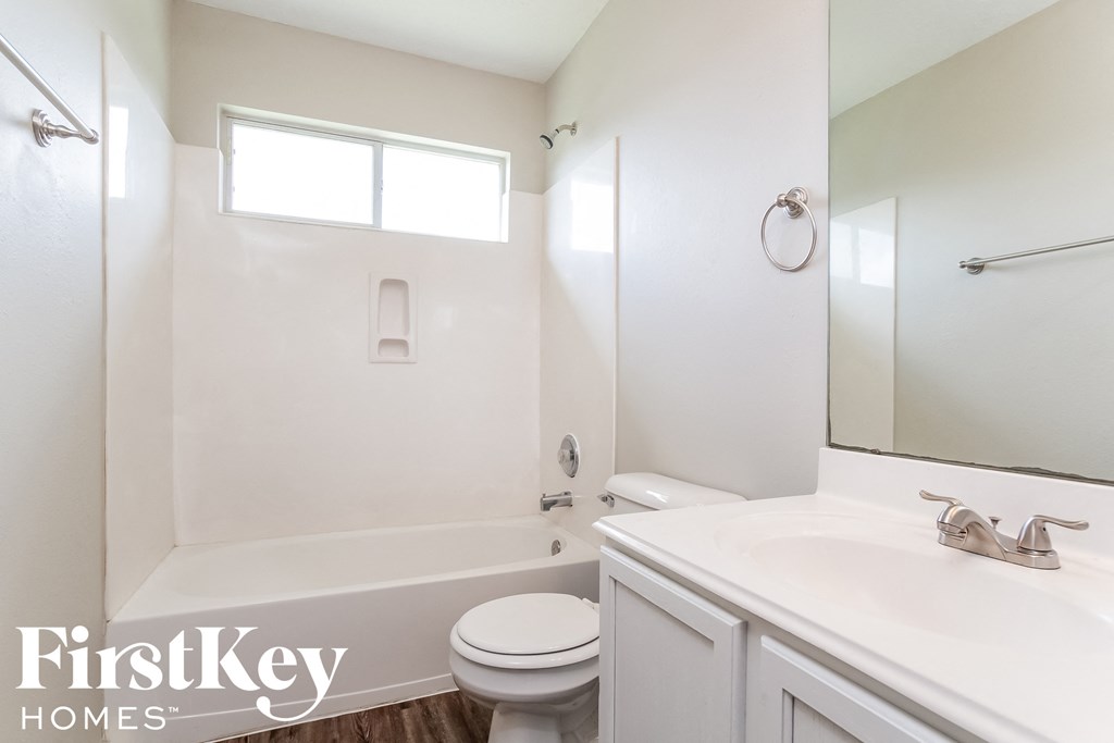 a white bathroom with a white sink and toilet and a bath tub