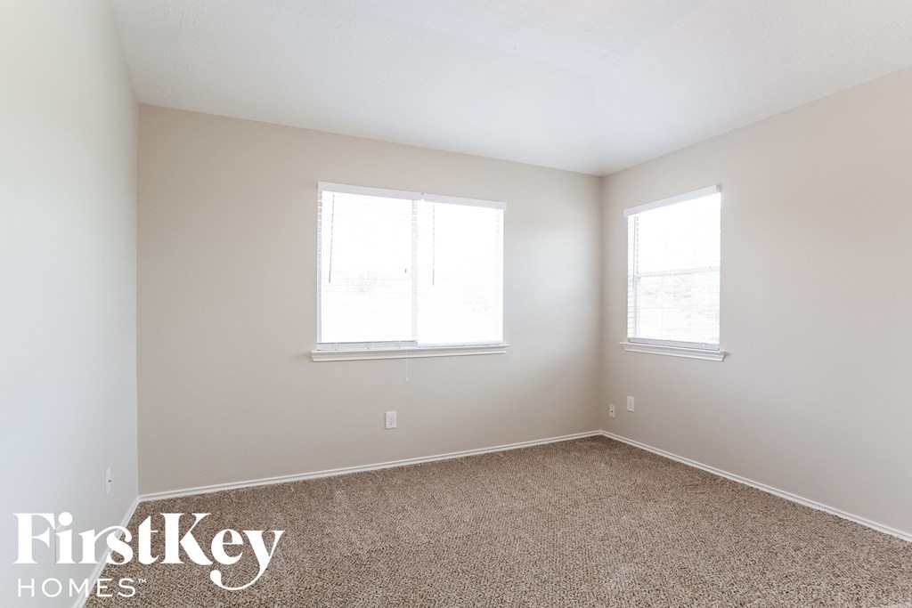 a bedroom with two windows and a carpeted floor