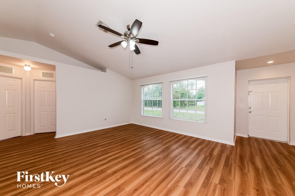 A room with a ceiling fan and wooden flooring.