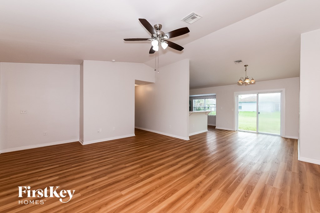 A spacious room with wooden flooring and a ceiling fan.