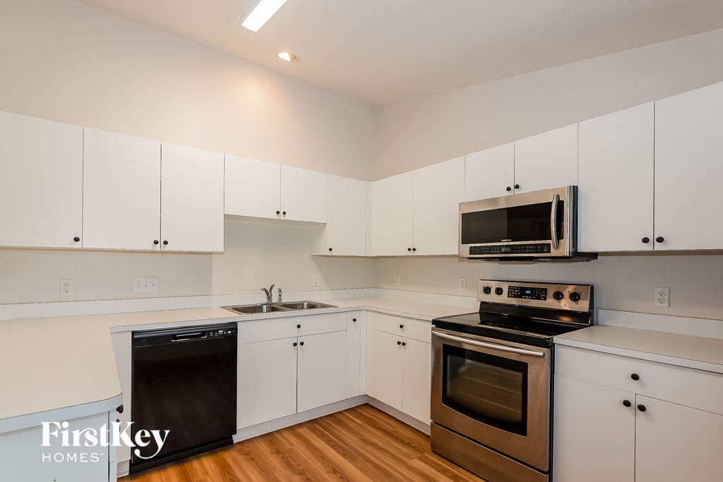 A kitchen with white cabinets and a black dishwasher.