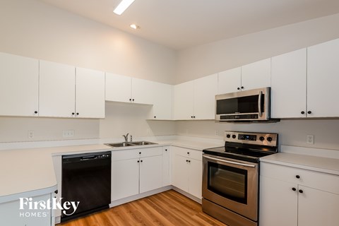 A kitchen with white cabinets and a black dishwasher.