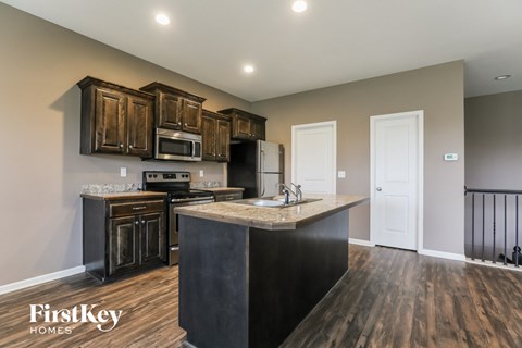 the kitchen is updated with stainless steel appliances and dark wood cabinets