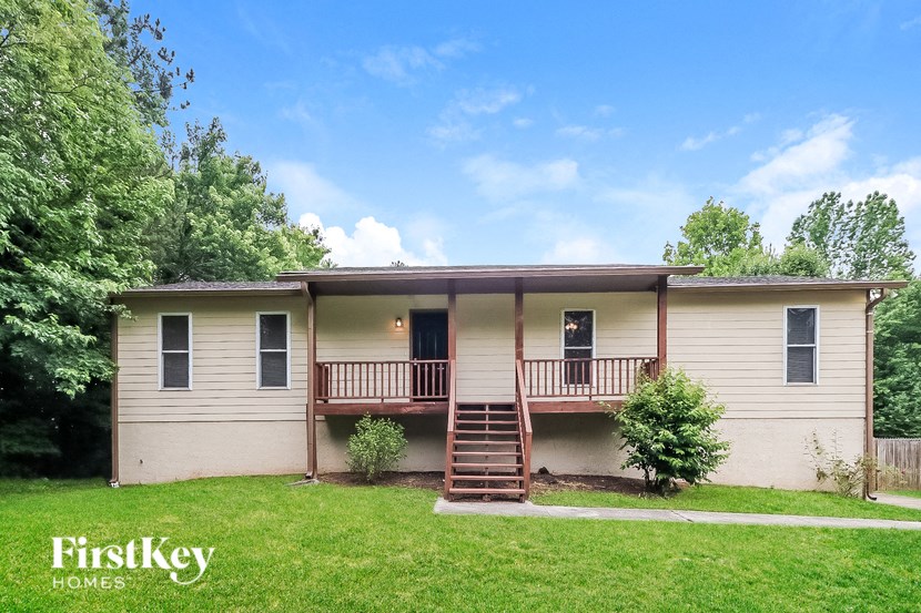 a cream colored house with a porch and a green lawn