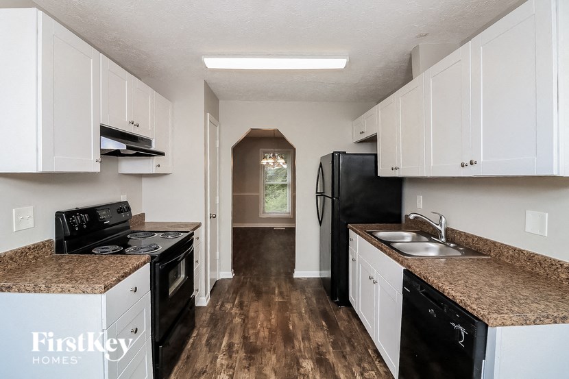 a kitchen with black appliances and granite counter tops and white cabinets