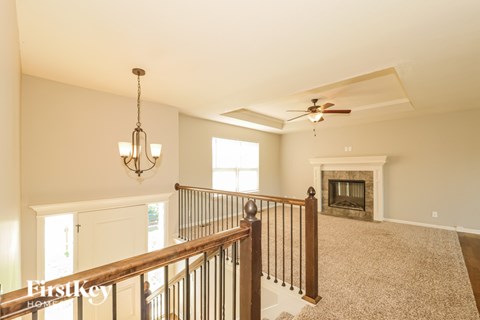 A spacious living room with a fireplace and a fan.