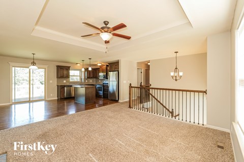 A spacious living room with a staircase and a ceiling fan.