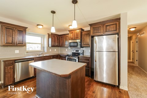 A kitchen with wooden cabinets and a stainless steel refrigerator.