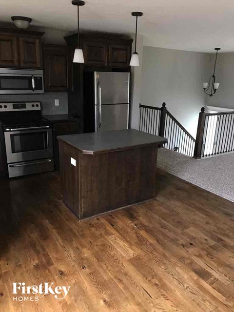 a kitchen with a island in the middle of a wooden floor