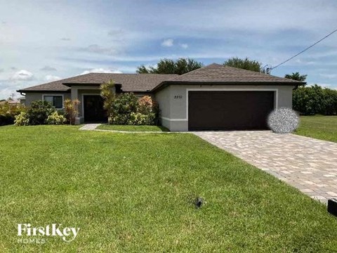 A house with a garage and a driveway in front of it.