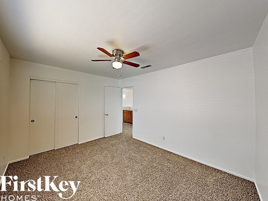 the living room has a ceiling fan and white walls