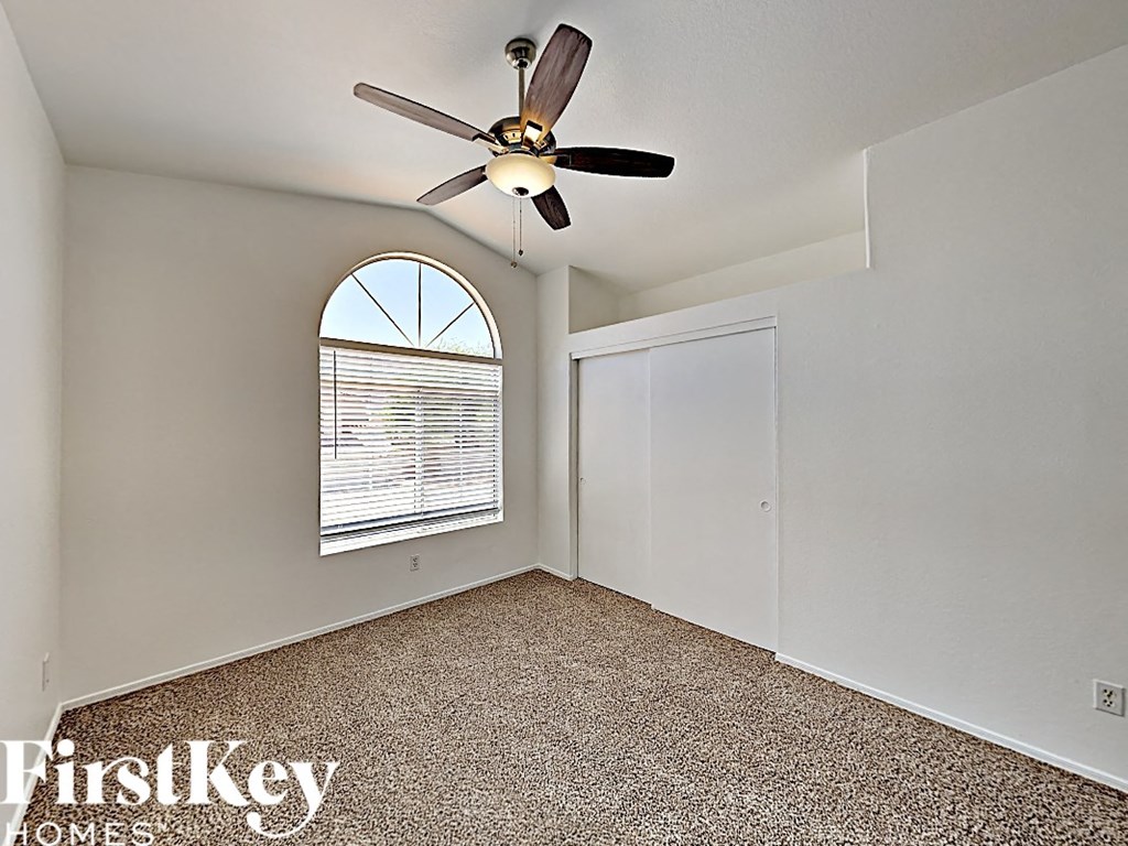 an empty bedroom with a ceiling fan and a window