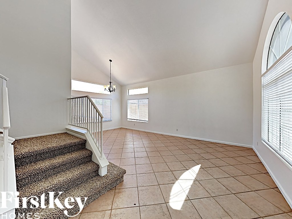 an empty living room with a staircase and a large window