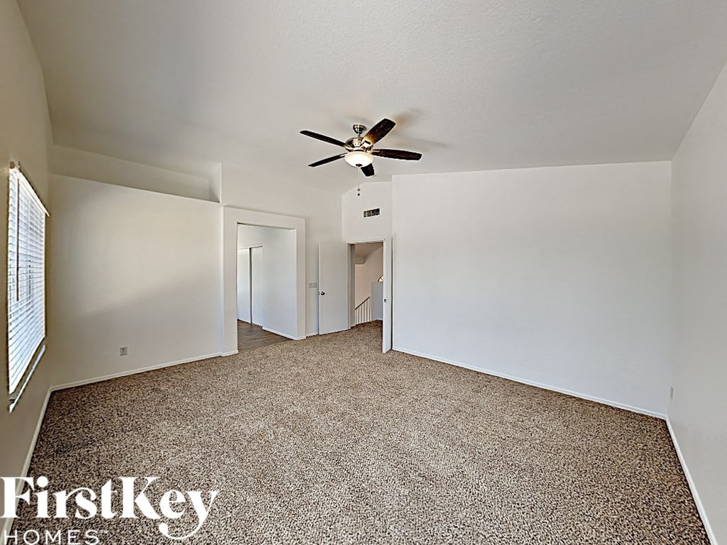 an empty living room with white walls and a ceiling fan