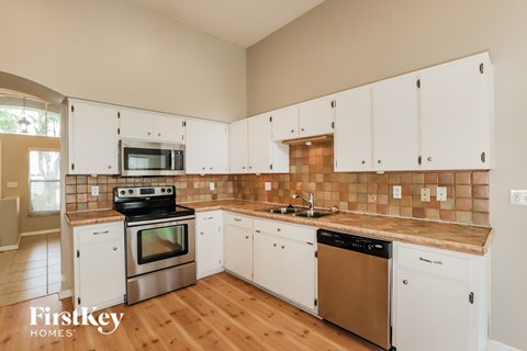 A kitchen with white cabinets and a tile backsplash.