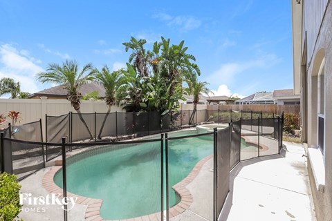 A pool surrounded by a black fence with a tree in the middle.
