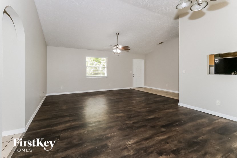 an empty living room with wood flooring and a ceiling fan