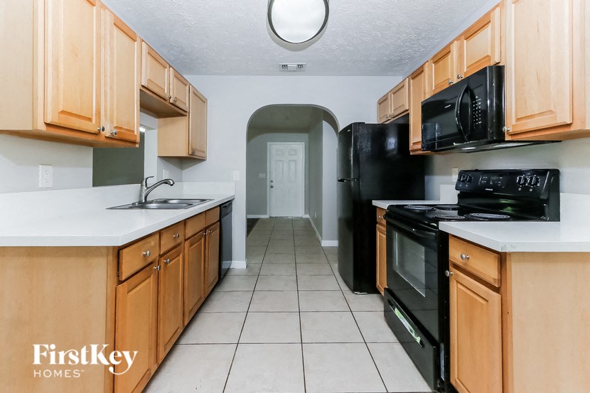 a kitchen with wood cabinets and black appliances and white counter tops