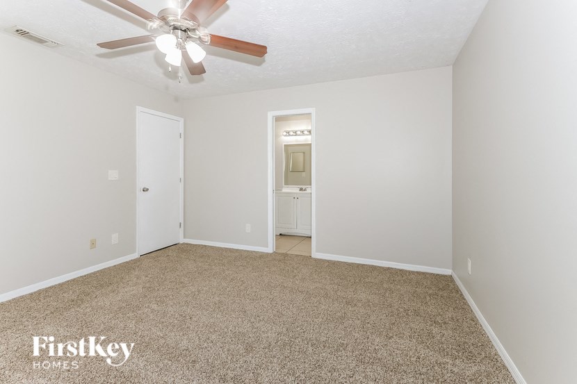 a spacious living room with carpet and a ceiling fan