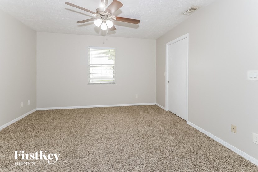a bedroom with a ceiling fan and a carpeted floor