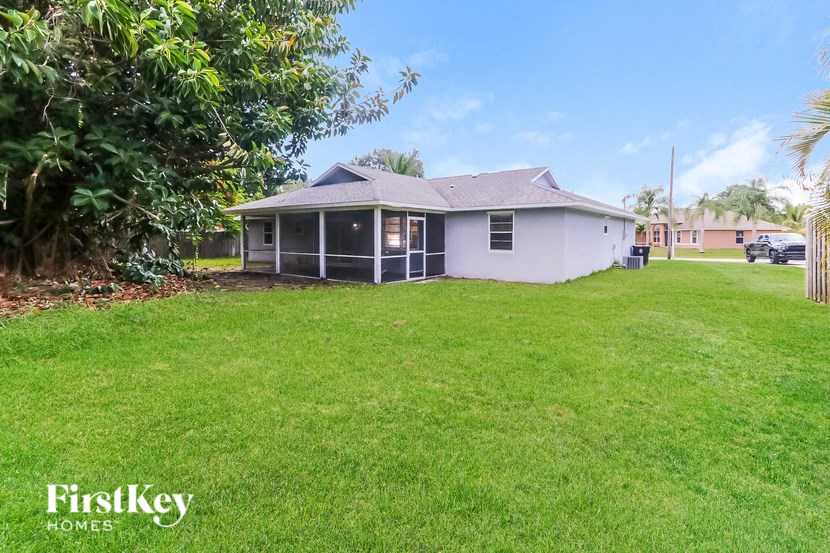 a white house with a grass yard and a palm tree