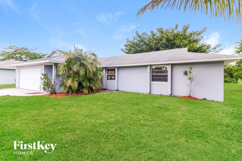a white house with a lawn and a palm tree