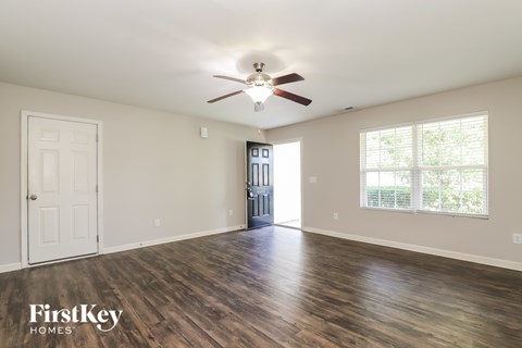 A spacious room with a ceiling fan and wooden flooring.