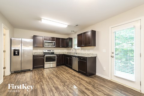 A kitchen with wooden floors and a refrigerator with a water dispenser.