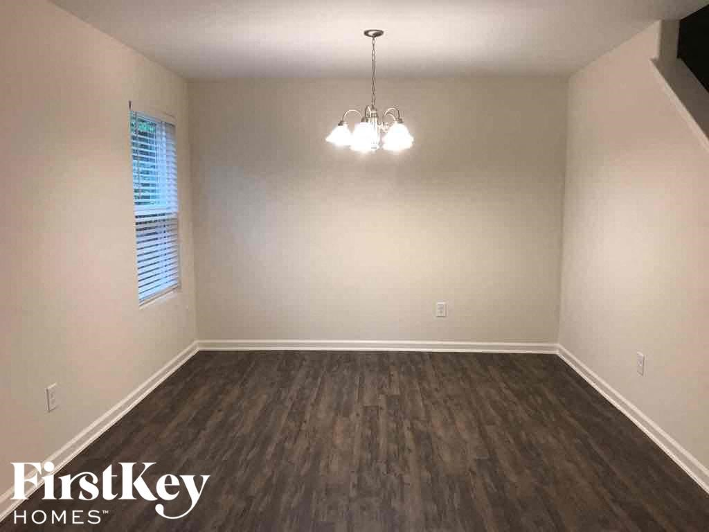 A room with wooden flooring and a chandelier hanging from the ceiling.