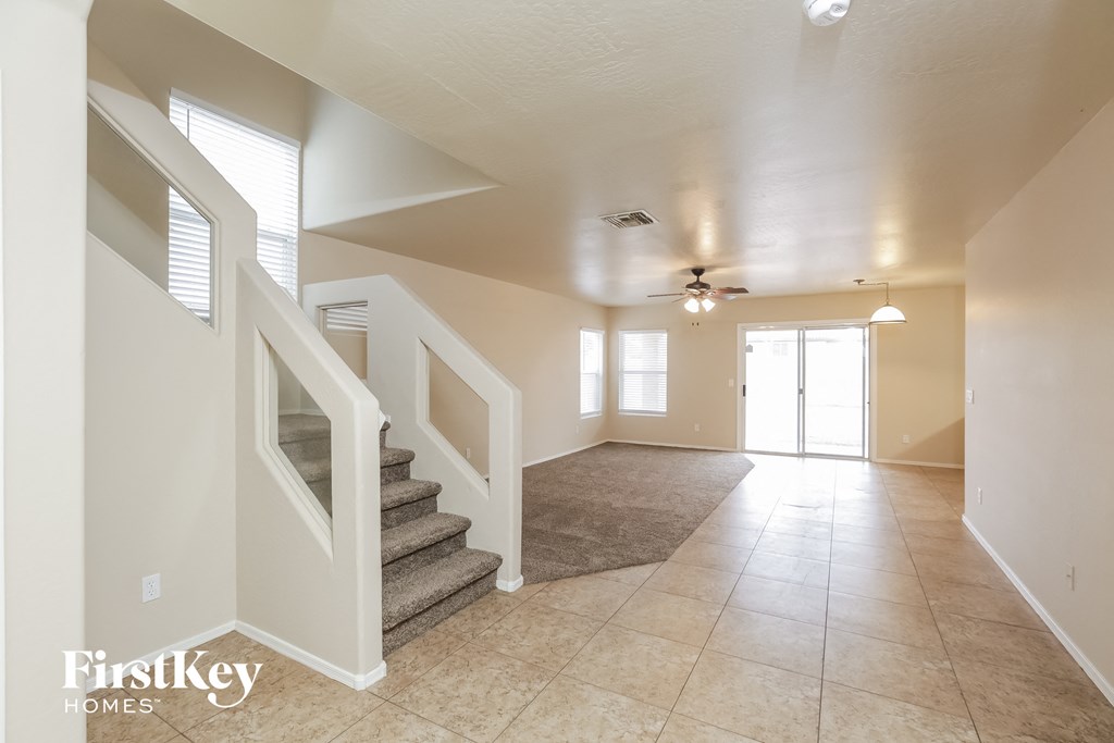 an empty living room with stairs and a ceiling fan