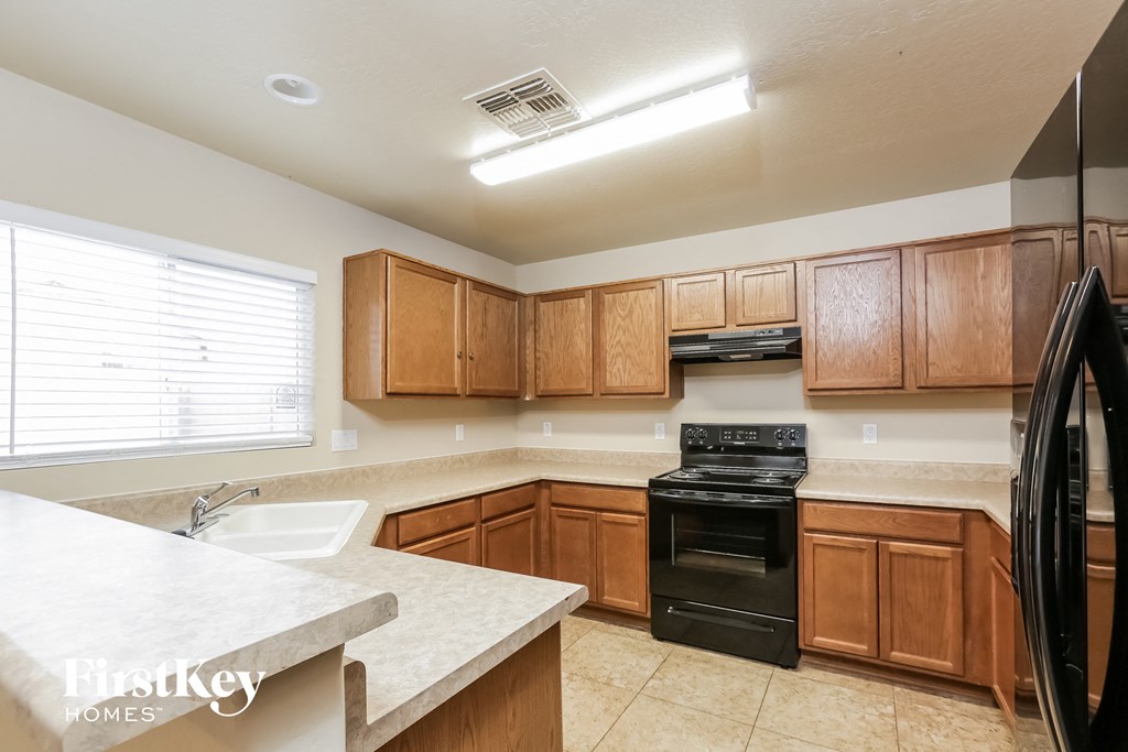 a kitchen with wooden cabinets and black appliances and white counter tops